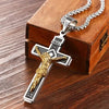 A gold-colored retro Christian cross amulet necklace displayed on a wooden box.