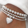 Silver minimalist round beaded bracelet set worn on a wrist.