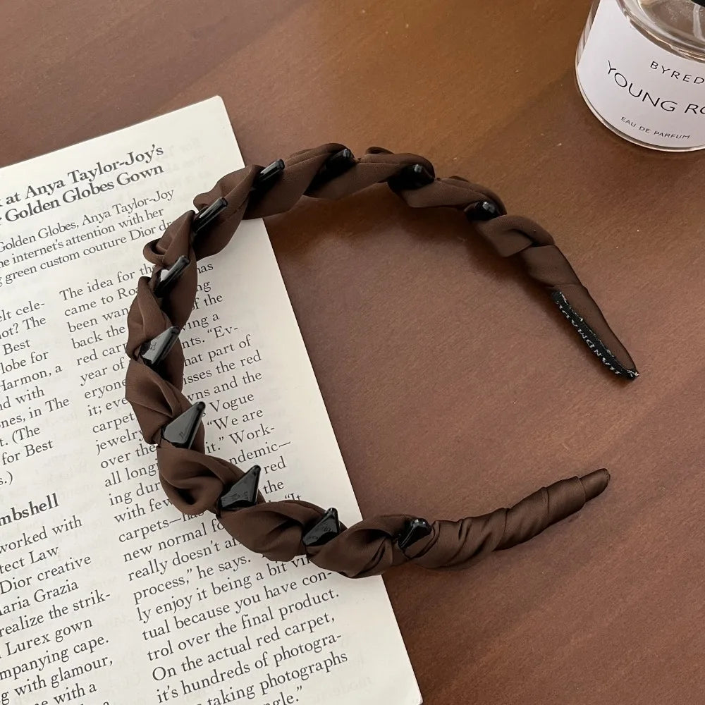 A close-up of a dark brown knotted hair headband with teeth resting on a piece of paper.