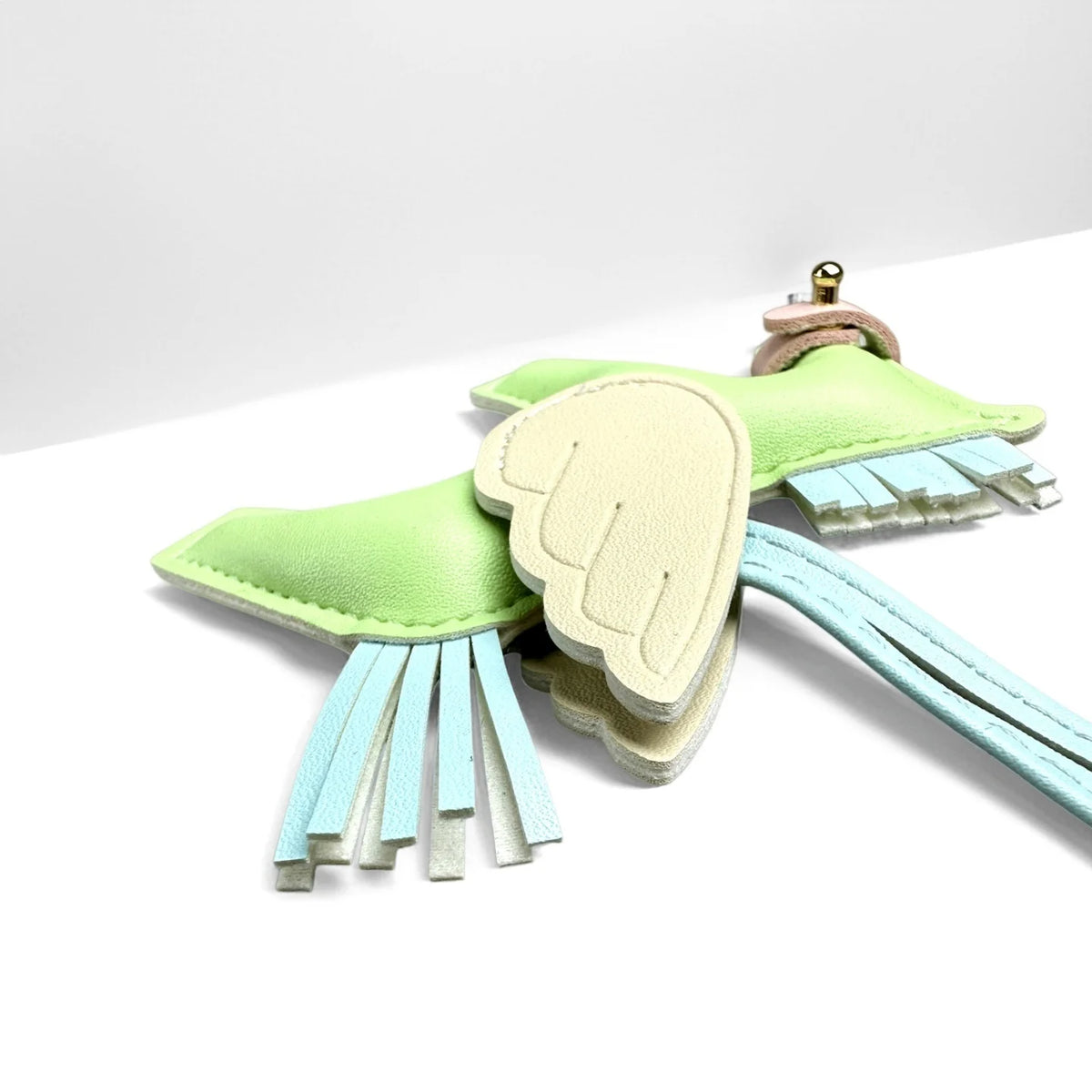 A light green winged pony keychain featuring soft felt wings and a pink leather loop.