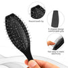 A black anti-static steel comb hair brush with round teeth and an S-shaped design shown being held by a hand.