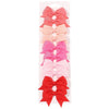 A set of pink and red handmade ribbon bow hair clips for kids displayed in a clear packaging.