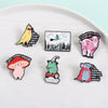 A collection of enamel pins featuring whimsical characters like a laughing yellow bird, a pink lamb, and a mushroom.