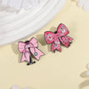 Pin de estetoscopio con lazo rosa y diseño de corazón en fondo claro.