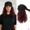 A model wearing a black t-shirt and a black adjustable short wave wig with long red curls.