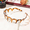 A close-up of a tortoiseshell acetate toothed headband resting on a white surface.
