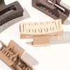 A set of seven square hair claw clips in a matte beige color shown from various angles.