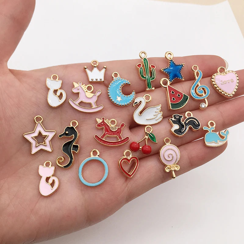 Une main tient une collection de charmets flottants en émail mélangés pour la fabrication de bijoux, représentant divers anim