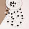 A collection of black and white mini flower hair clips scattered on a white surface.