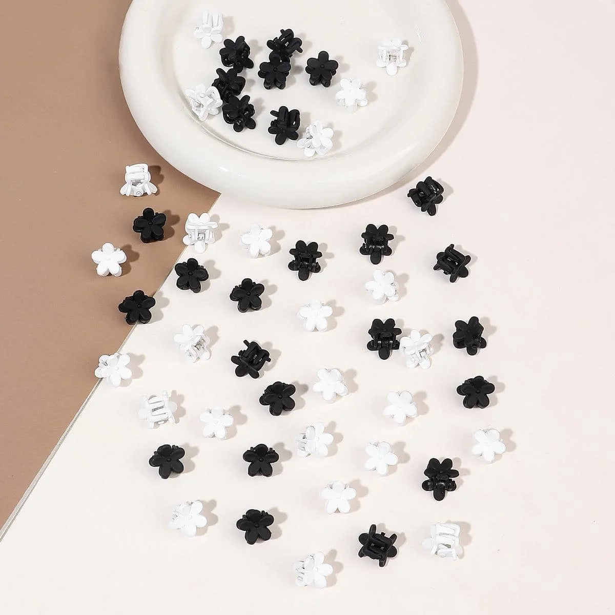 A collection of black and white mini flower hair clips scattered on a white surface.