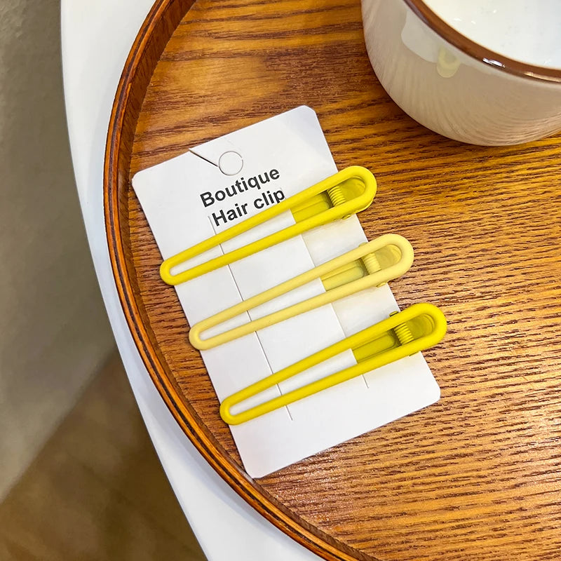 A set of five vintage frosted geometry hair clips displayed on a white card on a wooden surface.