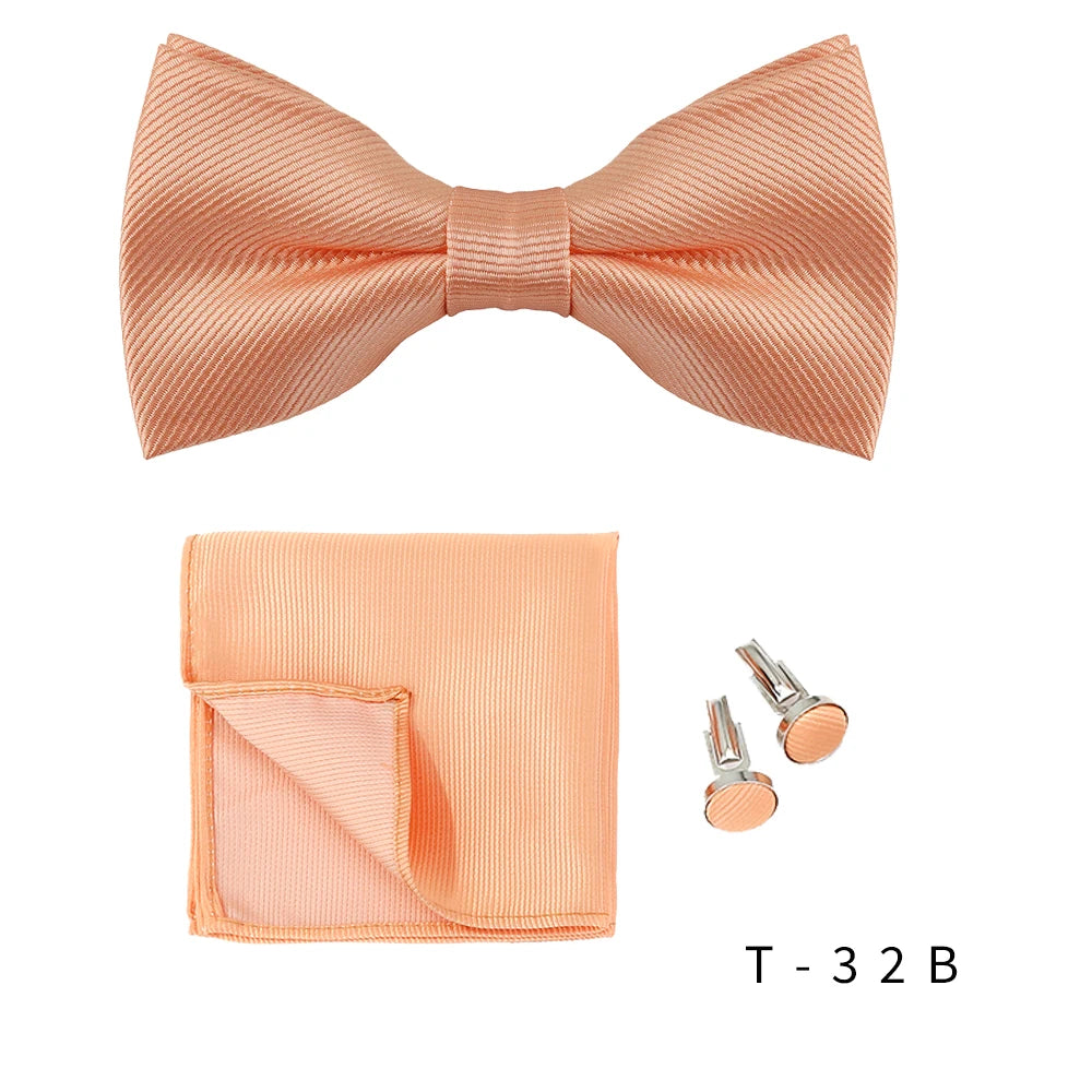 A peach colored men's bow tie and cufflinks set displayed on a white background.
