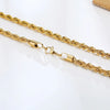 A delicate gold rope chain necklace lying on a white surface.
