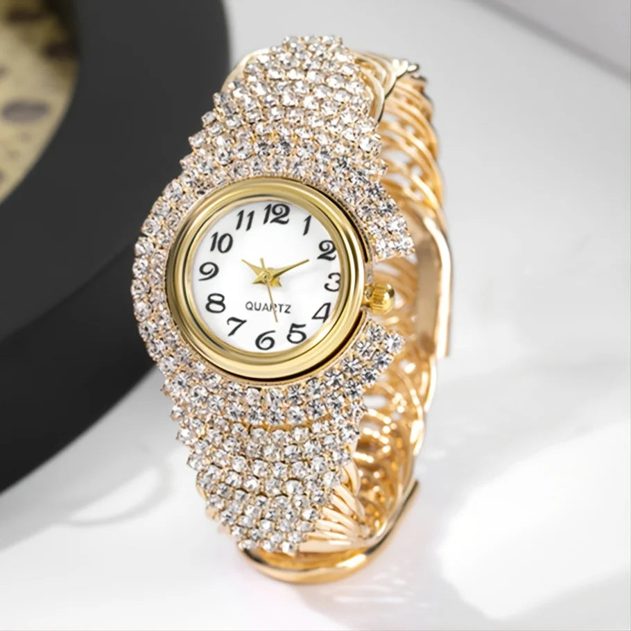 A close-up of an elegant gold quartz wristwatch fully encrusted with clear rhinestones on a white background.