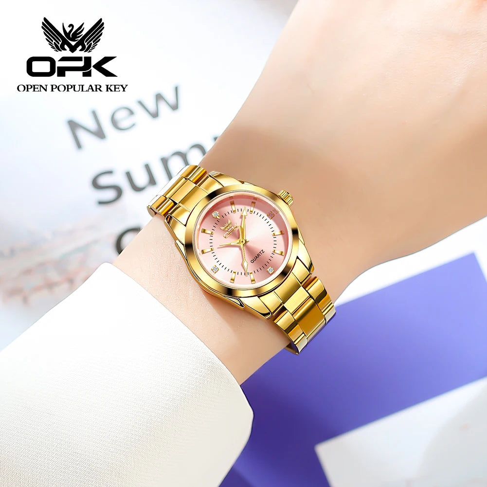 A gold-toned luminous quartz watch with a pink dial and rose gold accents worn on a wrist.
