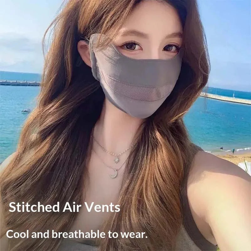 A woman models a gray stitched air vents face mask against a bright blue sea background.
