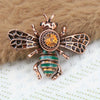 Broche antique en or, en forme d'abeille, avec des accents verts irisants et ambrés.