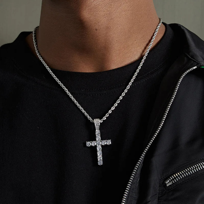 A close-up of a stainless steel cross pendant necklace worn against a black shirt.