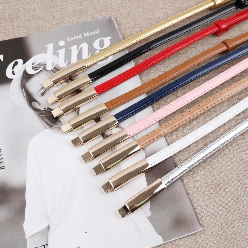 Eine Kollektion eleganter Slim-Gurtgürtel in verschiedenen Lederfarben und Goldverschluss, präsentiert auf einem Magazincover