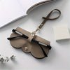 A tan PU leather pouch with a leather strap and silver hardware for storing eyeglasses.