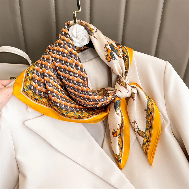A yellow silk scarf with an orange geometric pattern is tied around a white blazer and displayed on a hanger.