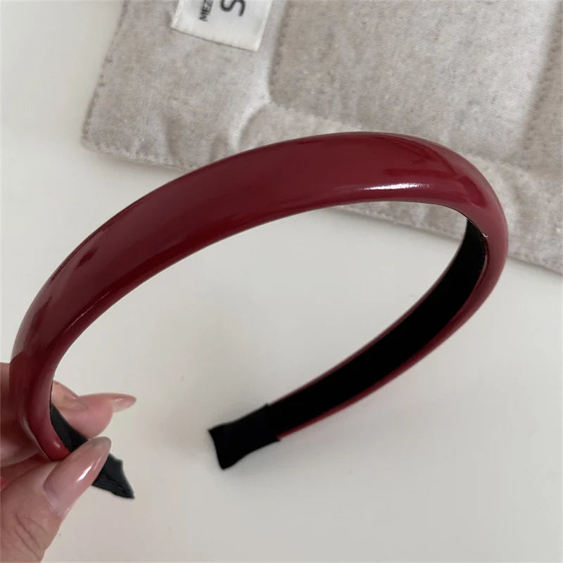 A maroon PU leather fashion headband is shown against a light gray background.