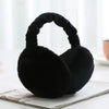 A black plush fur ear warmer earmuff resting on a white surface.