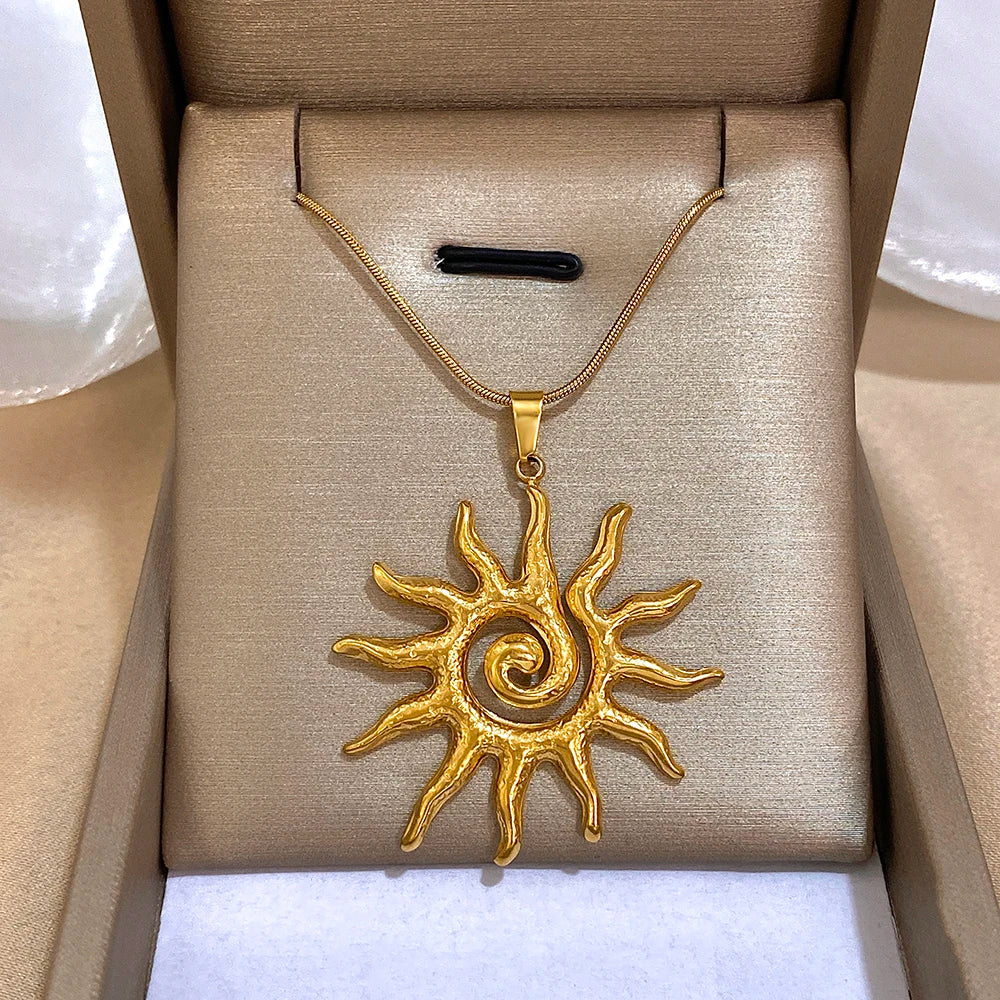 Collier fleur de soleil en spirale plaqué or, présenté dans une boîte brun clair.