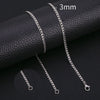 A close-up photo of a silver stainless steel Cuban link necklace with a 3mm chain, displayed on a black leather surface.