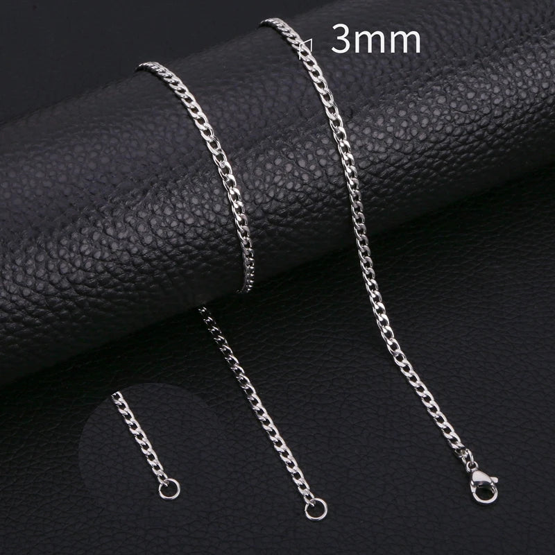 A close-up photo of a silver stainless steel Cuban link necklace with a 3mm chain, displayed on a black leather surface.
