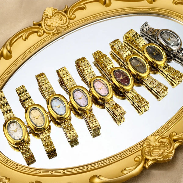 A collection of vintage-style watches with gold-toned cases and metal straps displayed on a gold-framed tray.