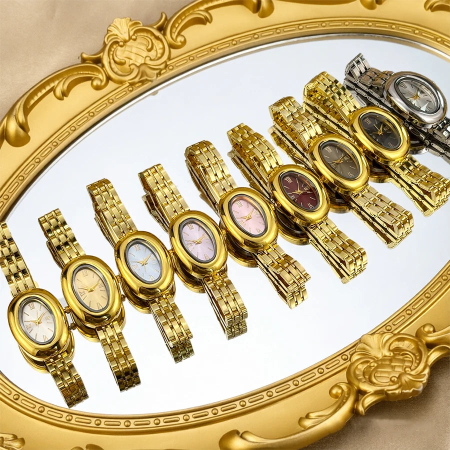 Colección de relojes estilo vintage con cajas doradas y correas de metal, exhibidos en una bandeja con marco dorado.