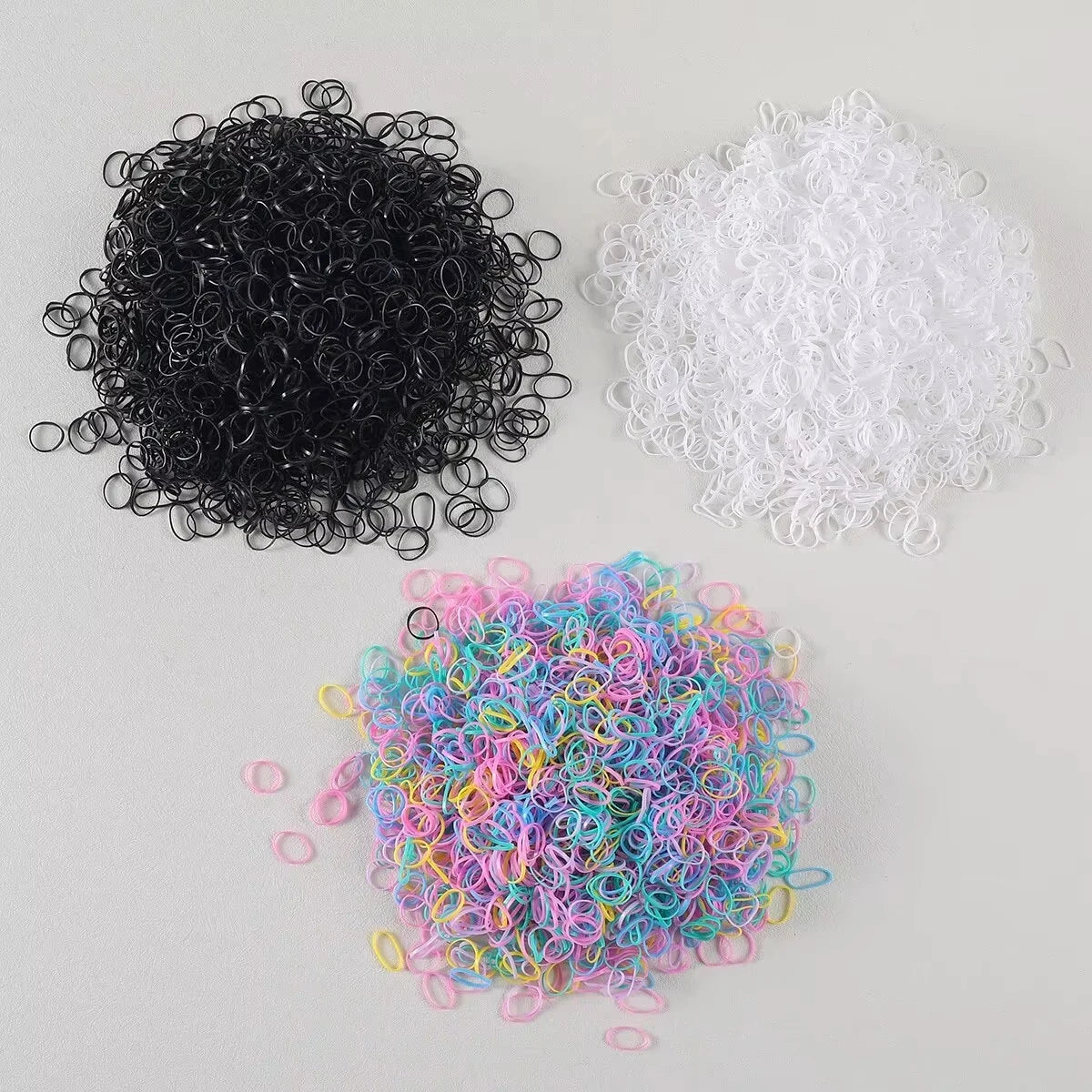 A collection of black, white, and multi-colored disposable rubber hair ties.