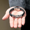 A hand holds a personalized leather knot bracelet with the inscription Love My Son.