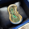 A vintage irregular quartz watch with a gold-toned case and green dial is displayed in a dark blue velvet box.