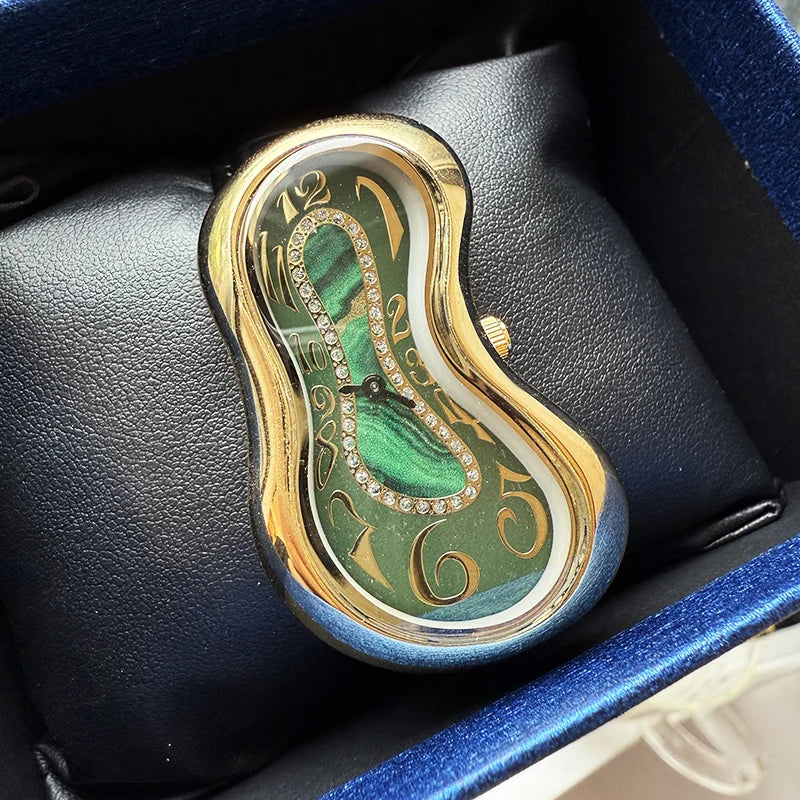 A vintage irregular quartz watch with a gold-toned case and green dial is displayed in a dark blue velvet box.