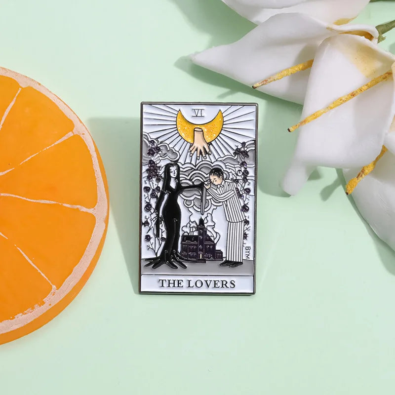 A tarot card enamel pin depicting The Lovers card with a female and male figure under a sun motif.