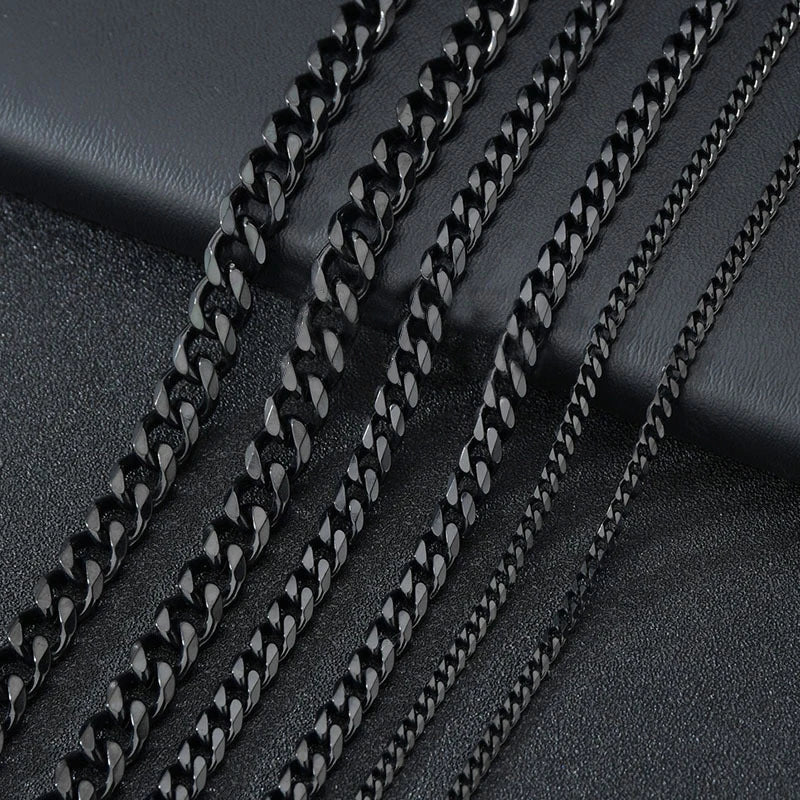 A close-up of multiple black Cuban link chains laid diagonally on a dark surface.