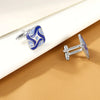Pince-cuffs argentés avec émail rayé bleu et blanc sur fond beige.