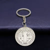A round silver medallion keychain featuring a depiction of St. Benedict.