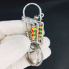 Une main tient une clé mécanique en acier inoxydable avec des accents émail colorés sur un fond sombre.