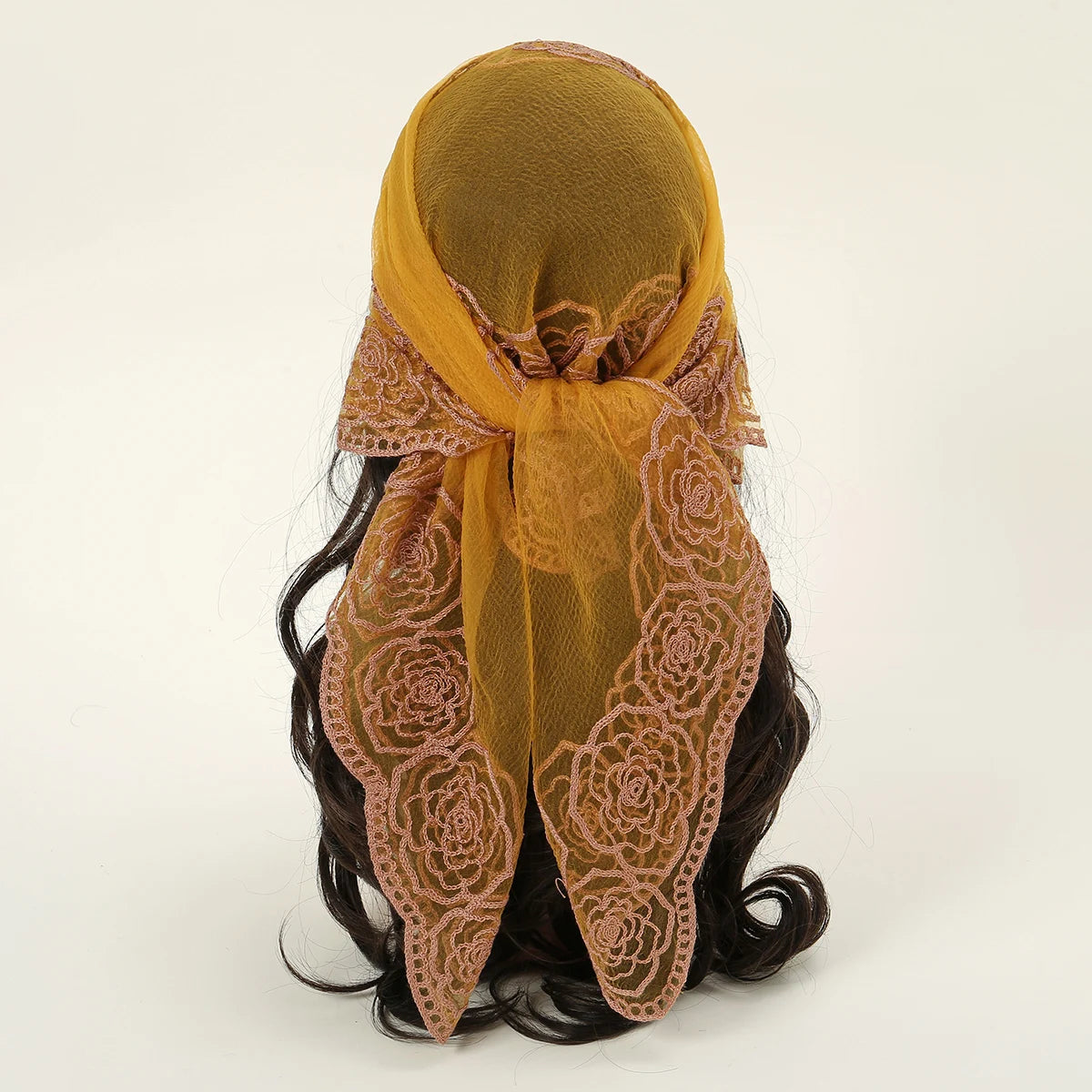 A mustard yellow floral embroidered lace bandana headscarf tied around dark hair.