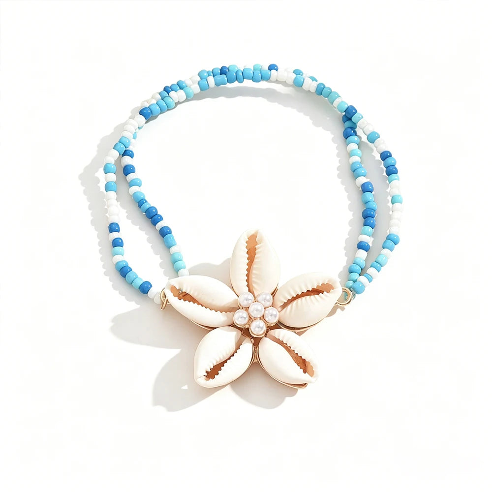 Boho cowrie shell anklet featuring white and blue beads and a flower charm