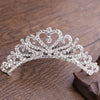 A sparkling crystal princess tiara hair comb for women displayed on a dark wooden surface.