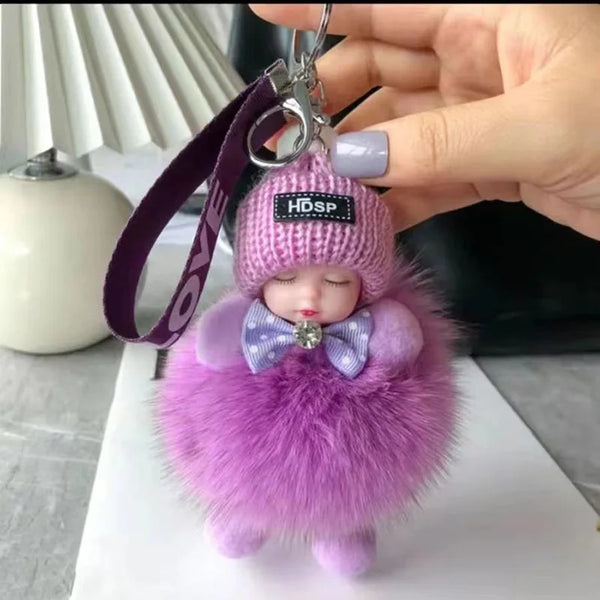 Poupée peluche violette et duveteuse avec bonnet et nœud rose, tenue à une clé USB.