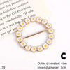 A gold-toned button clip made of white and yellow floral rhinestones is shown against a piece of paper.