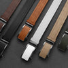 A collection of men's leather belts in various colors and finishes laid diagonally on a dark surface.