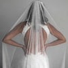 Vista trasera de una novia con un velo nupcial de perlas transparentes y un peine sobre su cabello y vestido de novia blanco
