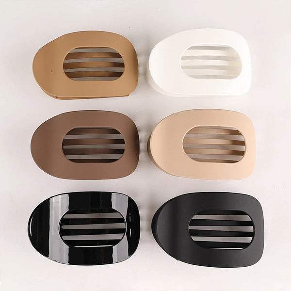 A set of five flat circular hair clips in beige, white, brown, and black finishes.