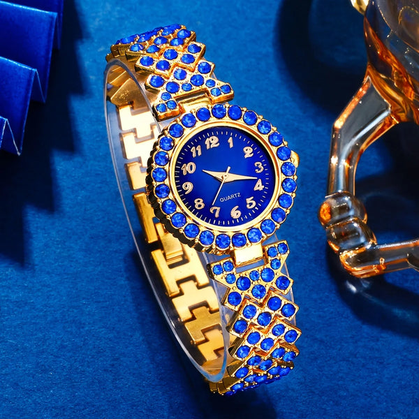 A gold-toned ladies quartz wristwatch with blue accents and a sapphire crystal case displayed on a blue velvet surface.